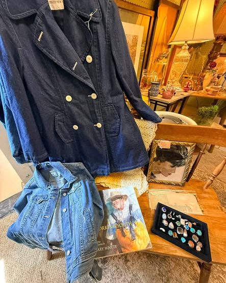 A vintage denim jacket, an art book, and a tray of rings arranged on a wooden chair
